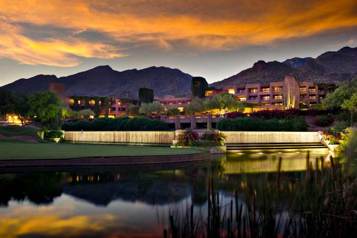 Long exposure of a luxury hotel resort.  A golf course and pond is in the foreground and foothill mountains  in the background.