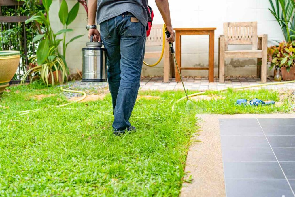  A pest exterminator sprays a home’s backyard for termites.